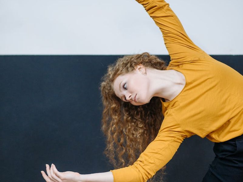Person performing a dynamic stretching movement in a spacious room.